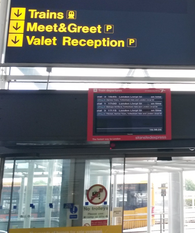 [Stansted Airport]Whilst the railway (to London) is mentioned 'air side' on the concourse there is just a small ticket office, which could be easily confused with coaches, and a single direction sign for "trains", with an information screen below it. Why is there no large rail 'double-arrow' sign?