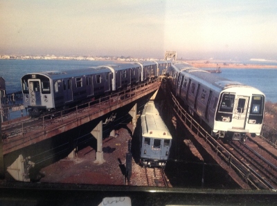 [New York]This MTA postcard shows the evolution of three types of trains on the New York Subway. Amazingly the picture was taken on the A Subway line to JFK Airport and Far Rockaway. The views are more akin to the Florida Keys than a subway system. A ride beyond the airport certainly beats waiting too long in the departure lounge and costs nothing if you do not leave the statin at the far end and just return to Howard Beach for the Skytrain to JFK